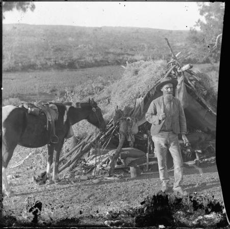 A prospector and his horse in camp
