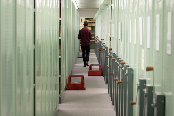 A staff member walking down a row of compactus storage units in the STAX area