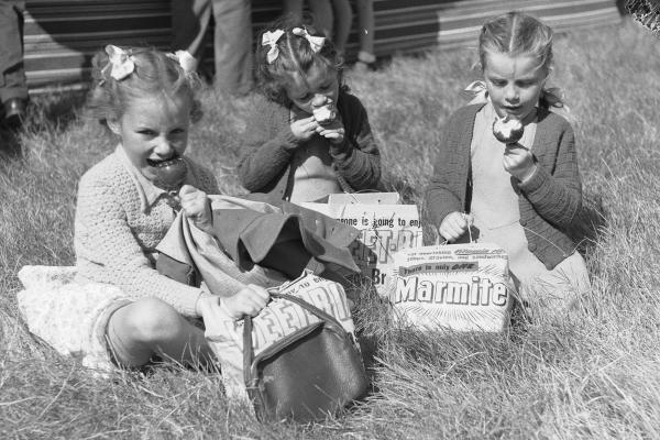 Girls eat toffee apples and inspect their show bags 1949