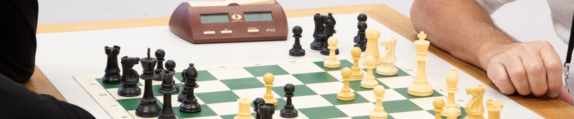A chess board and a glimpse of two people sitting on either side